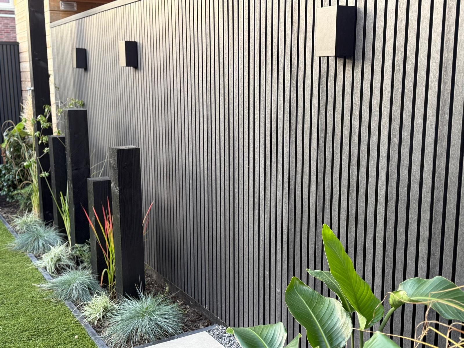 Black vertical composite slats on a garden wall with black steel posts