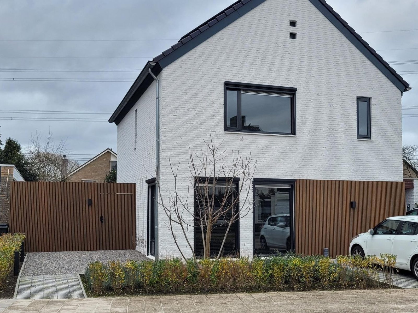 White detached house with a walnut slat facade on the ground floor